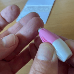Place the lancet on the side of the fingertip you have chosen. Press down firmly until it clicks (the white tip should retract).